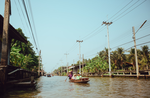 Tourist are escorted in a narrow boat along the canals of the Damnoen Saduak Floating Market