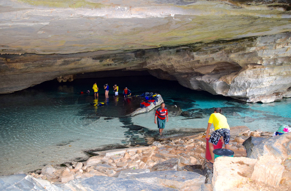 A tour group entering a water-filled cave in swimming gear