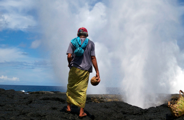 A local Samoan man holding a coconut near blowholes