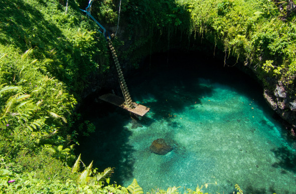 A deep hole with clear water and a ladder