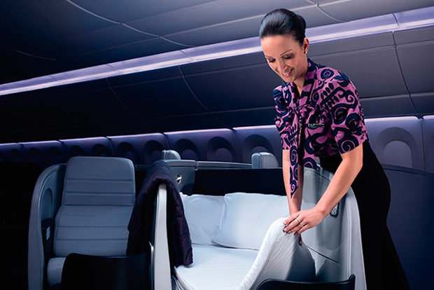 An Air New Zealand flight attendant setting up a lie-flat business class seat