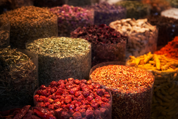 Rows of containers holding colourful spices at a market 