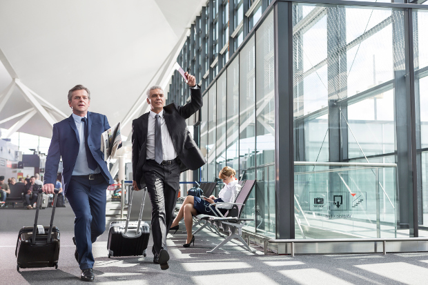 Two business men rushing through the airport with their carry-ons to catch their flight